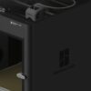 Close up of a dark Bambu Lab 3D printer showing the front panel with the Bambu Lab logo and visible internal belt drive