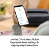 Hand holding a smartphone showing a Cricut heat guide screen with 315°F for 30 seconds and setup steps in view